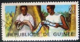 Selo postal comemorativo da República da Guiné 1967  Men Holding Rock Python